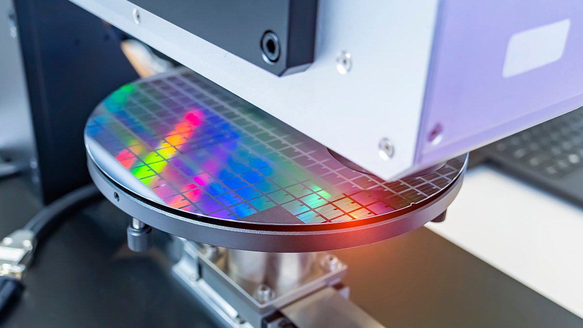 Close-up of semiconductor wafer under inspection equipment with colorful reflections